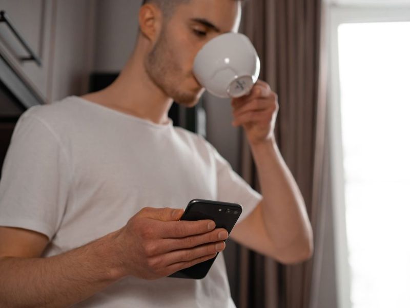 A tradesperson drinking coffee while checking today's job on a phone